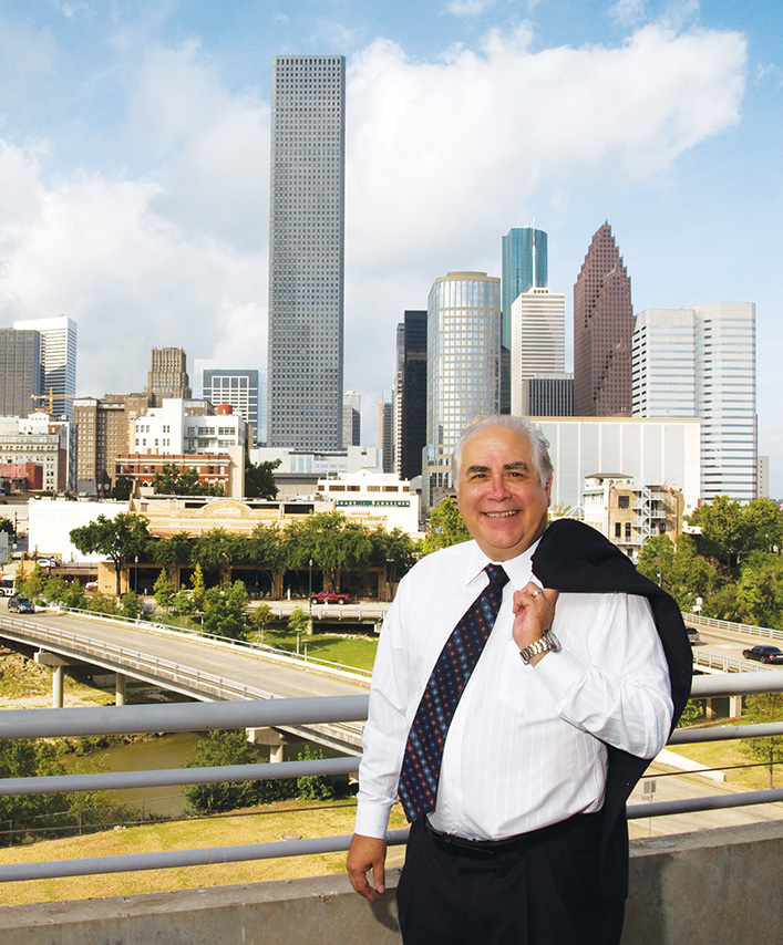 William V. Flores, looking relaxed in a portrait with the Houston skyline in the background.