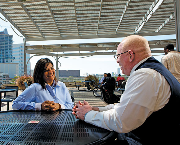 Faiza Khoja and Vida Robertson seated across from one another at an outdoor table